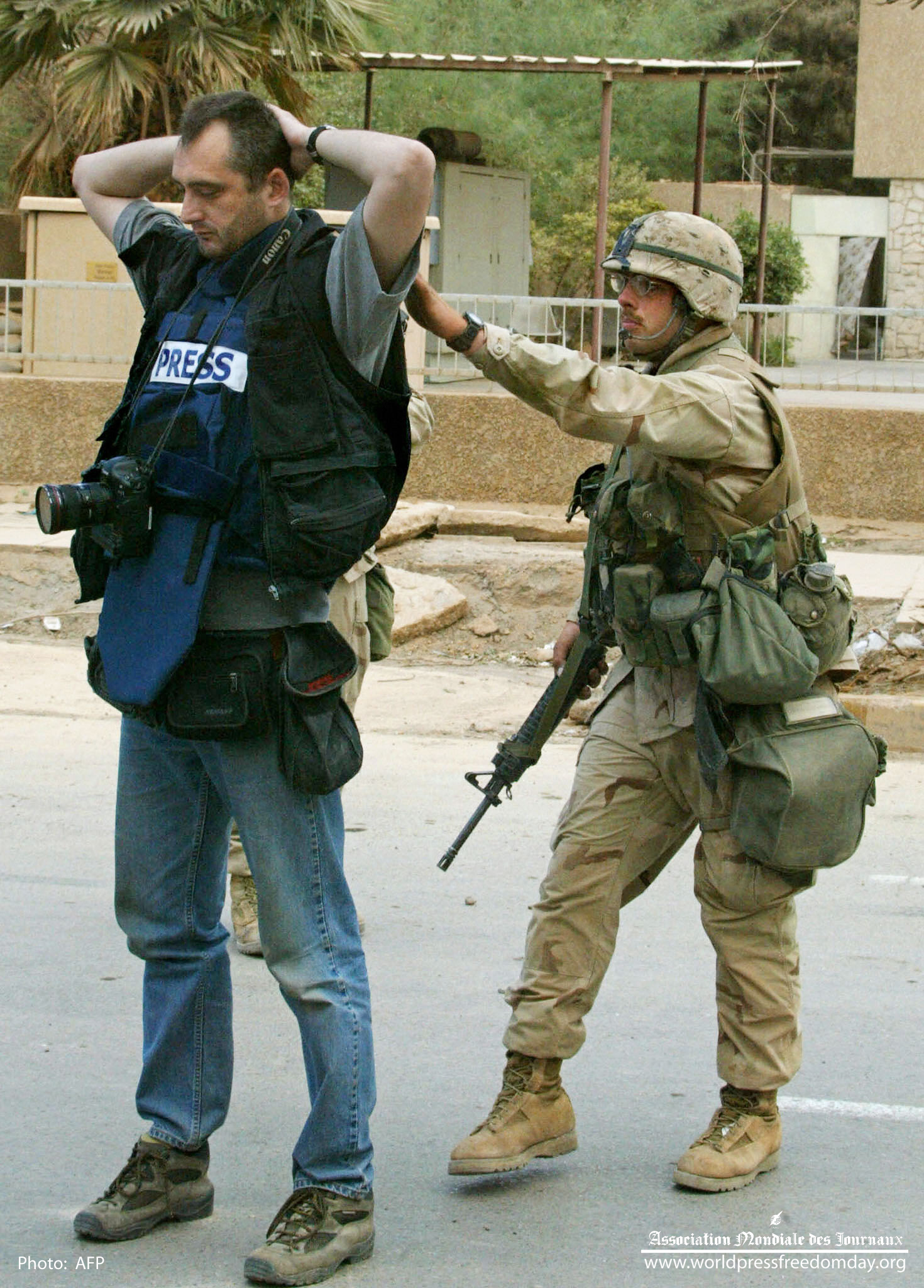 'n Amerikaanse soldaat deursoek Reuters se fotograaf, Goran Tomasevic by 'n padblokkade naby die Palestynse hotel in Baghdad 10 April 2003.   Foto: AFP /PATRICK BAZ 