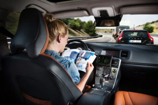 Foto: Die dame agter die stuur van ‘n selfbestuur-Volvo lees terwyl die motor sy weg self vind. 