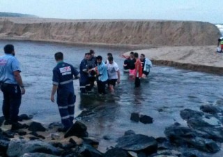 Paramedici van Netcare 911 dra die beseerde man deur die water en oor die rotse by Mtwalumi-strand op 1 April 2015 Foto: Netcare 911