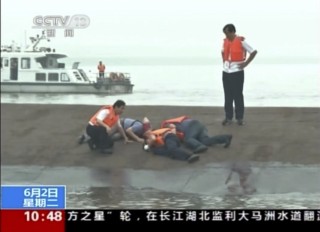 Reddingswerkers op die omgeslaande veerboot. Foto: CCTV via AP Video