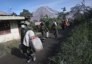 Indonesiese soldate dra persone se besittings uit die gevaarsone ná berg Sinabung op 21 Mei 2016 in Sumatra, Indonesië uitgebars het. (Foto: AP Photo/Binsar Bakkara)