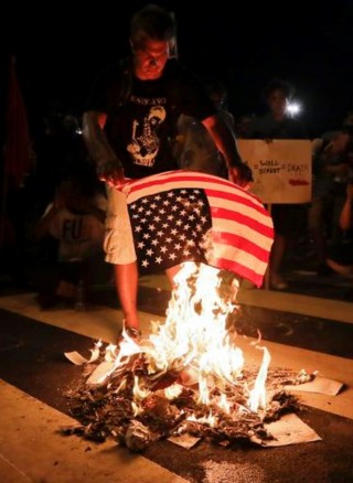  ŉ Betoger verbrand ŉ Amerikaanse vlag tydens ŉ optog in Philadelphia, in die VSA, gedurende die tweede dag van die Demokratiese Nasionale Konvensie. Foto: AP Photo/Matt Slocum/ wire.africannewsagency.com