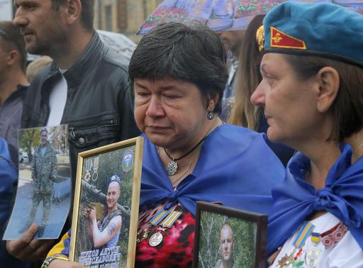 Naasbestaandes in Kiev hou foto’s vas van hul familielede wat as soldate gesterf het in gevegte met die pro-Russiese seperatiste by ŉ Onafhanklikheidsdagoptog. AP Photo/Efrem Lukatsky