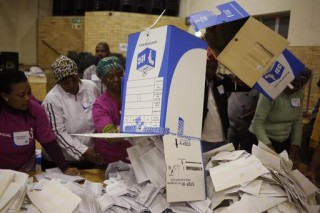 Verkiesingbeamptes begin Woensdagaand die eerste klomp stembriewe tel by ŉ stemstasie in Manenberg net buite Kaapstad. Foto: AP Photo/Schalk van Zuydam