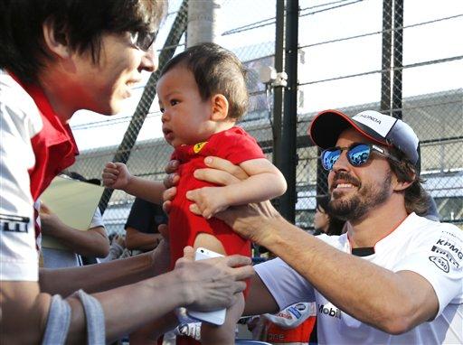 Die McLaren-renjaer, Fernando Alonso van Spanje, hou ŉ kind van ŉ aanhanger vas by die Suzuka-renbaan in Suzuka in Japan. Die Japanese Formule Een Grand Prix vind Sondag daar plaas. Foto: AP Photo/Toru Takahash 