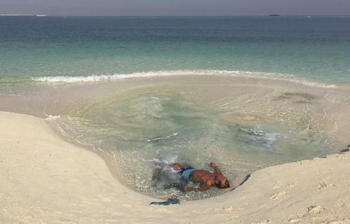 ŉ Man baai in die vlakwater op ŉ strand in Dubai. Foto: Kamran Jebreili / AP