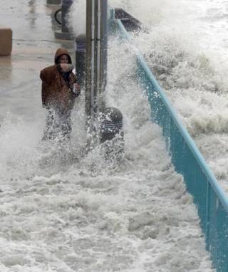 Brian Johns word deur vloedwater getref terwyl hy ŉ video probeer neem in Daytona Beach, Florida (7 Oktober 2016). Foto: AP/Eric Gay