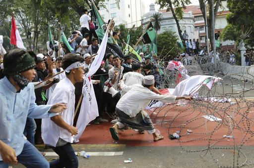 Moslembetogers trek aan lemmetjiesdraad wat ŉ pad versper wat na die presidensiële paleis lei. Daar is ŉ betoging aan die gang teen die Djakartaanse goewerneur, Basuki Tjahaja Purnama, in Djakarta, Indonesië. Foto: AP Photo/Tatan Syuflana